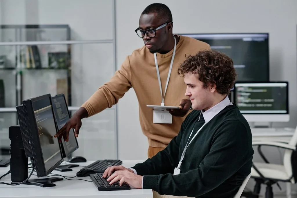 Two computer systems analysts collaborating on coding tasks