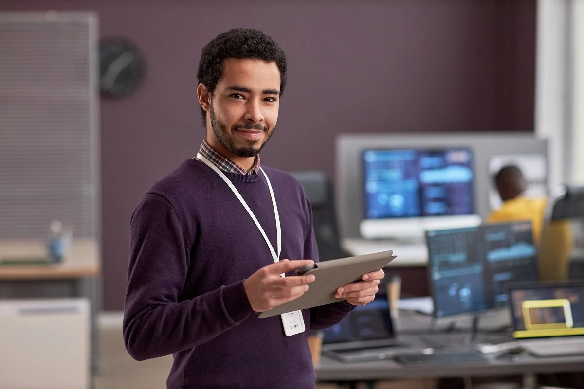 computer systems analyst holding tablet in it room