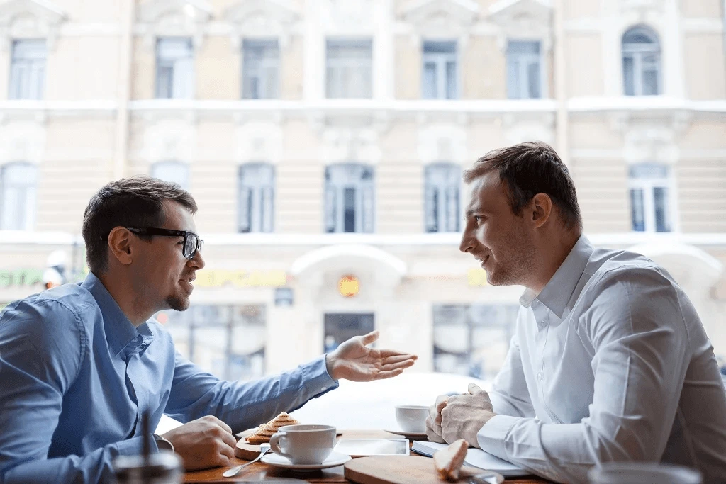 two workmates talking to each other in a cafe